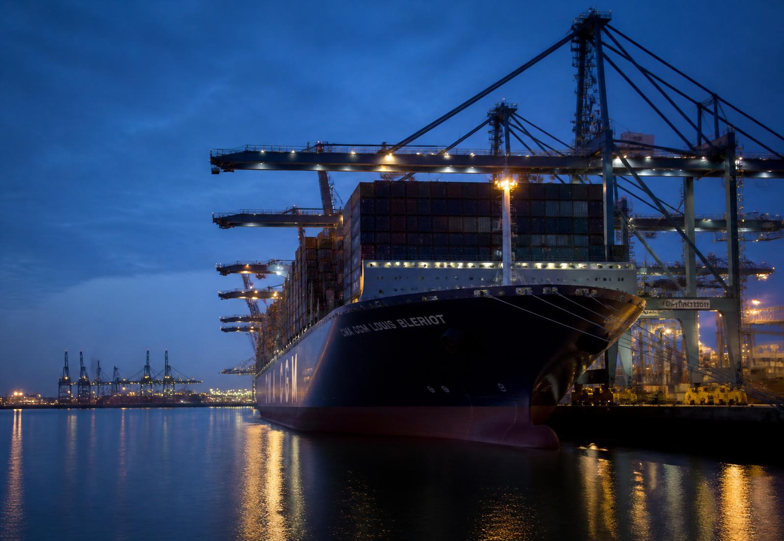 Container ship loading at a UK port at dusk